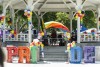 A gazebo is decorated with balloons and large letter spelling out Pride in rainbow colors